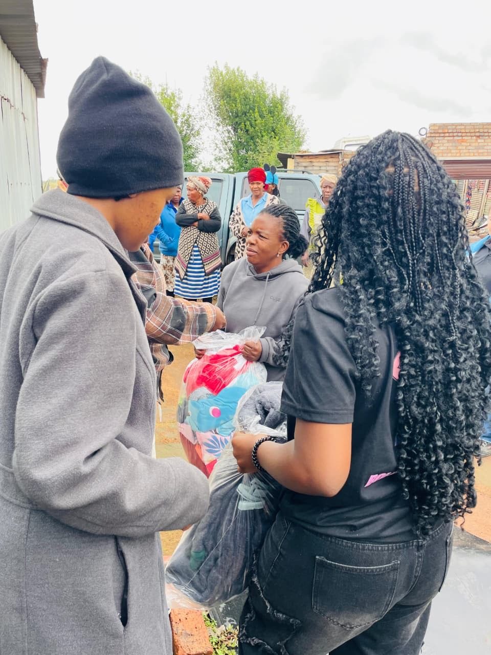 Volunteer handing over donated winter clothing to a community member
