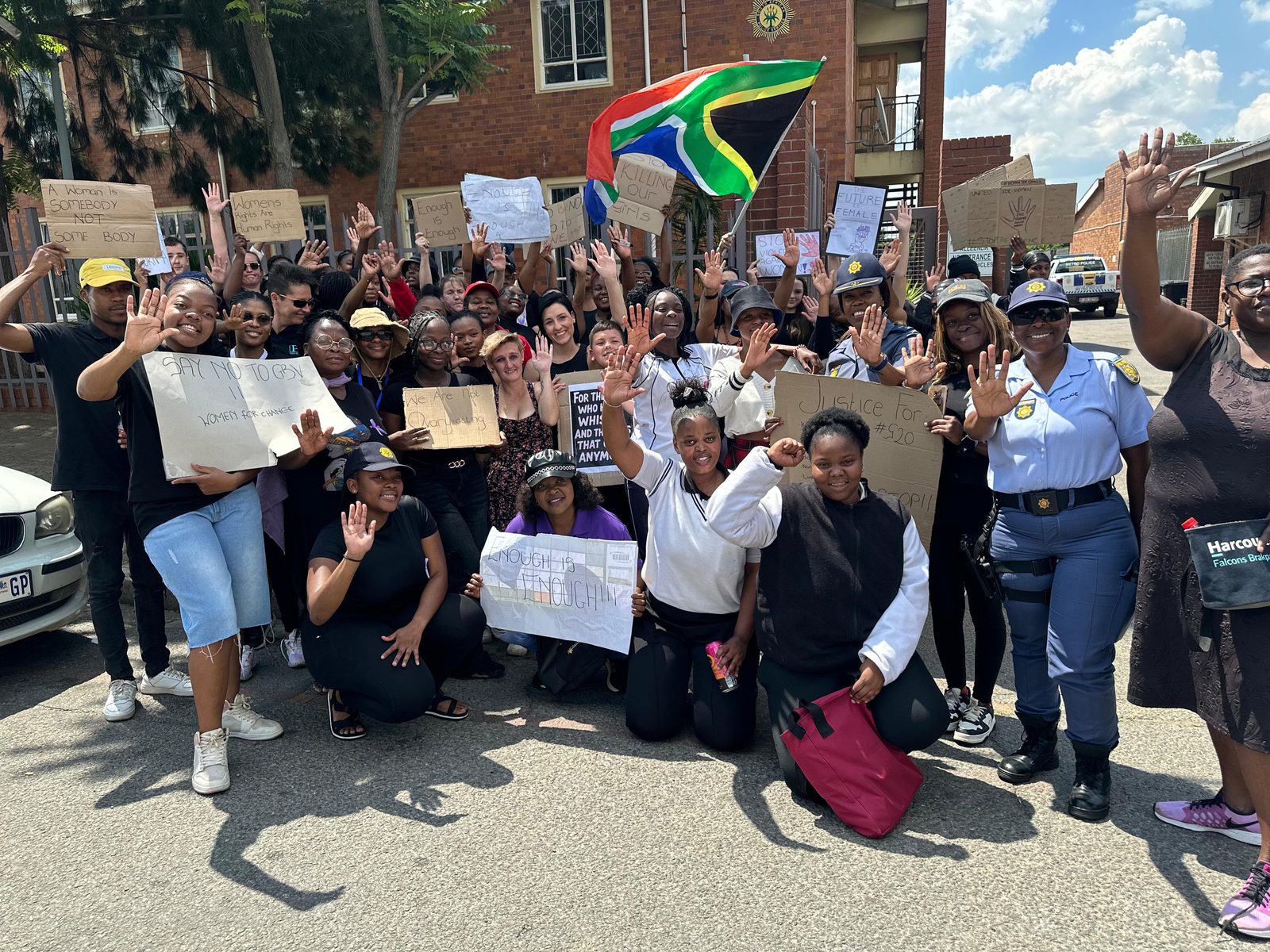 Large crowd of marchers holding placards and the South African flag at a GBV awareness march