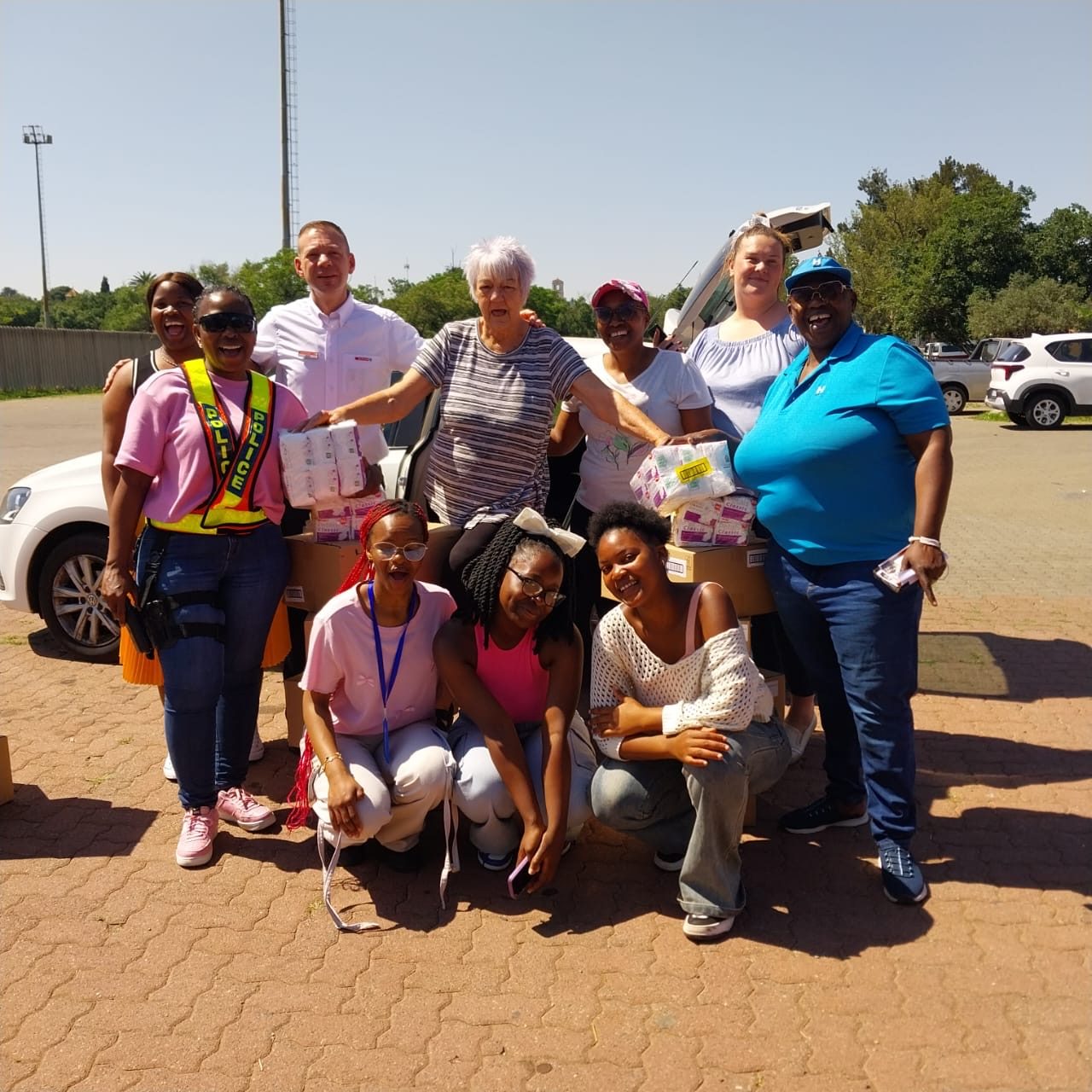 Volunteers and community partners handing over boxes of sanitary products