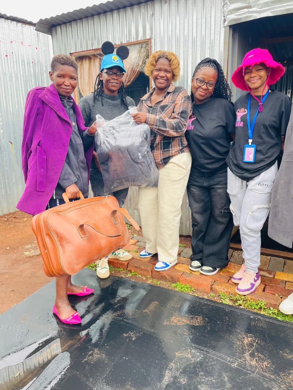 Volunteers delivering clothing and a suitcase of essentials during a home outreach visit